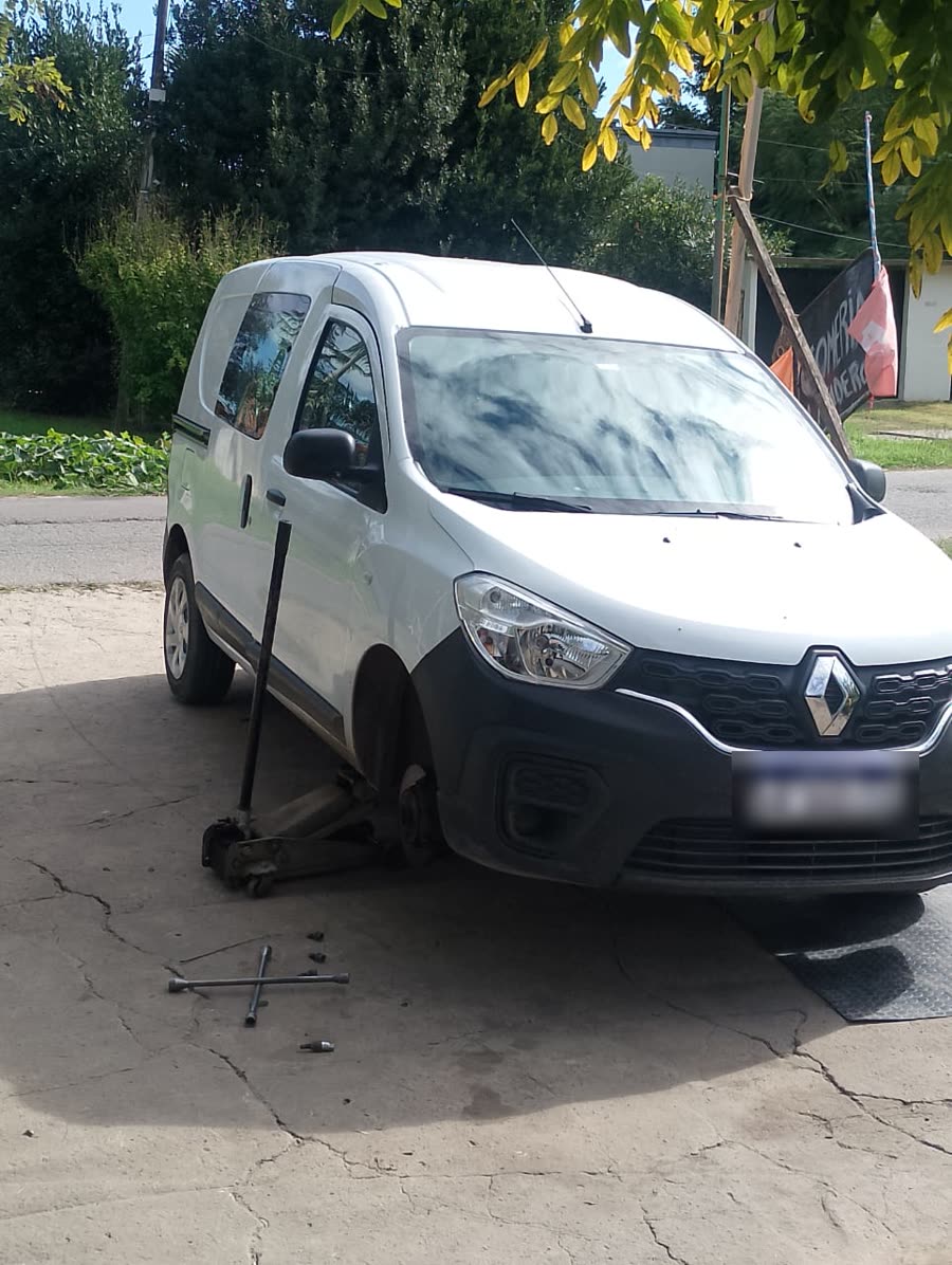 Una Renault Kangoo levantada con el crique y sin una rueda, en la vereda del taller