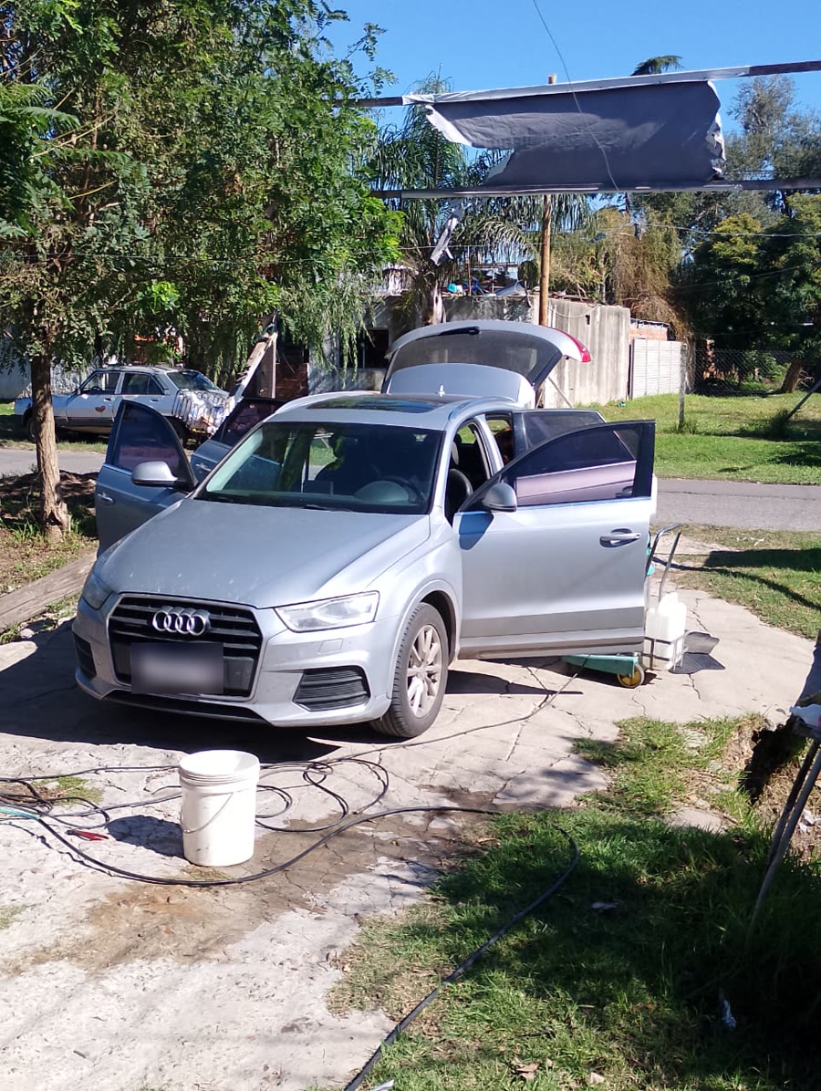 Un Audi gris con las puertas y el baúl abiertos, en pleno lavado